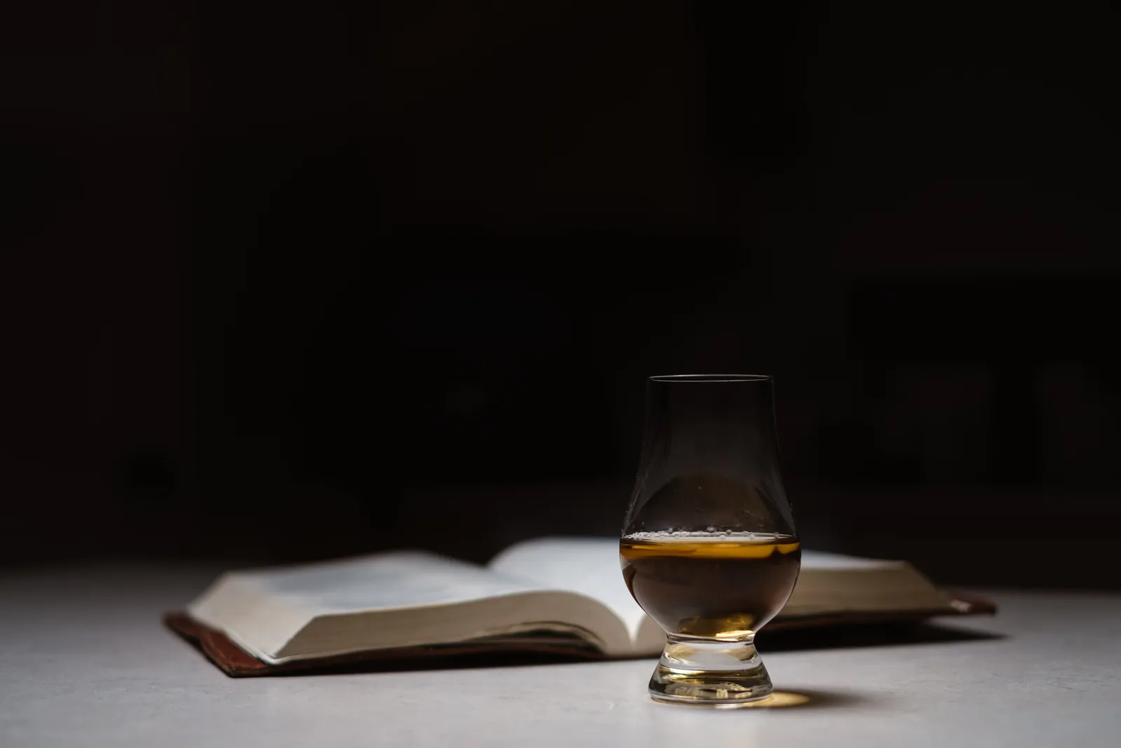 A glass of whisky beside an open book